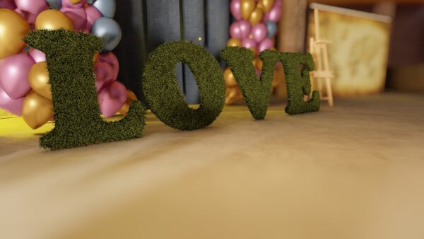Lettres LOVE en gazon synthétique pour la décoration de mariage, posées au sol avec un fond de ballons.